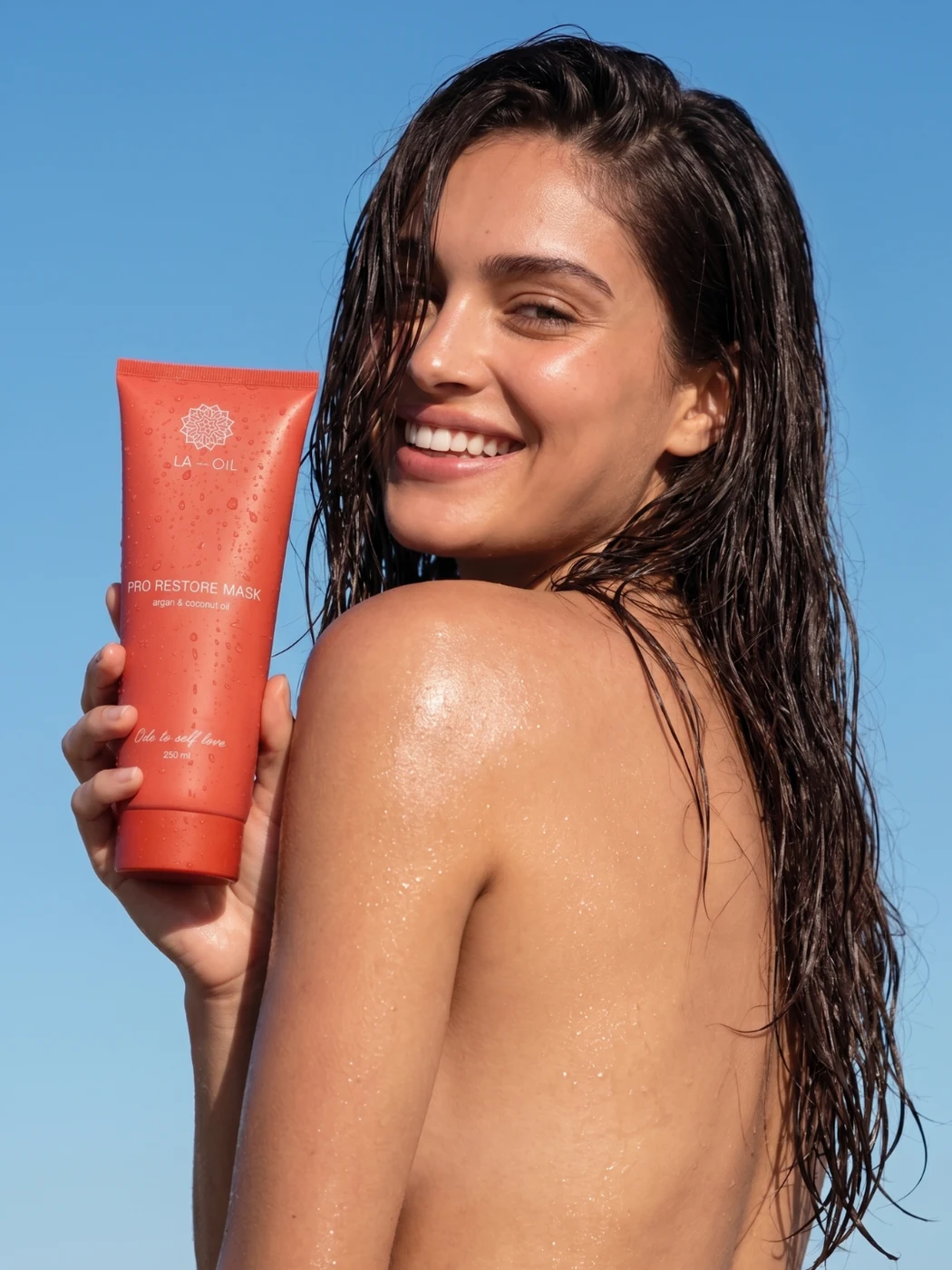 LA-OIL campaign with a model holding the orange Pro Restore hair mask tube